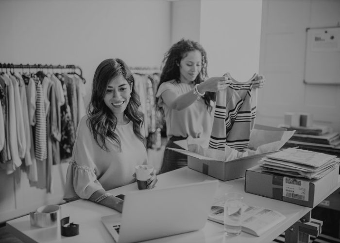 Working women at their store. They wearing casual clothing, accepting new orders online and packing merchandise for customer